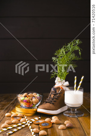 Dutch holiday postcard Sinterklaas. Wooden background with childrens shoe with carrots for Santa's Dutch holiday postcard Sinterklaas. Wooden background with childrens shoe with carrots for Santa's 71420516