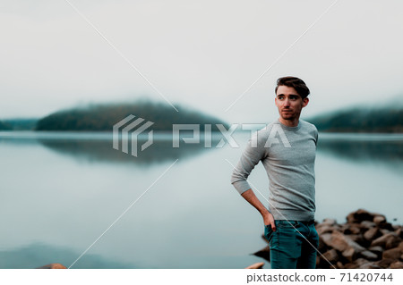 Portrait of young male model on a rainy day with a beautiful lake in the background Portrait of young male model on a rainy day with a beautiful lake in the background 71420744