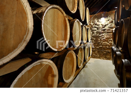 Rows of alcoholic barrels are kept in stock. Distillery. Cognac, whiskey, wine, brandy. Alcohol in barrels, alcohol storage Rows of alcoholic barrels are kept in stock. Distillery. Cognac, whiskey, wine, brandy. Alcohol in barrels, alcohol storage 71421357