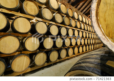 Rows of alcohol barrels in stock. Distillery. Cognac, whiskey, wine, brandy. Alcohol in barrels 71421363