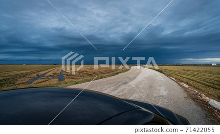 Black car driving along curved road towards the storm Black car driving along curved road towards the storm 71422055