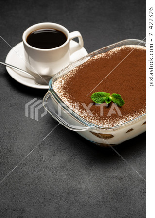 Traditional Italian Tiramisu dessert in glass baking dish and cup of fresh hot espresso coffee on concrete background Traditional Italian Tiramisu dessert in glass baking dish and cup of fresh hot espresso coffee on concrete background 71422326