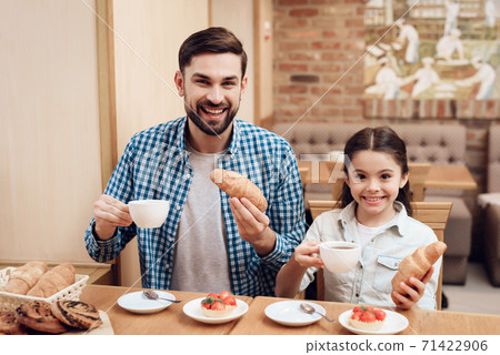 Father with Daughter Eating Cakes in Cafeteria. 71422906
