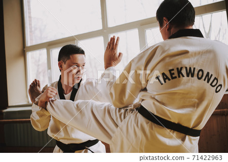 Two men practicing taekwondo together in the gym. Two men practicing taekwondo together in the gym. 71422963