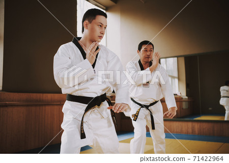 Men stand in a rack and practice karate techniques Men stand in a rack and practice karate techniques 71422964
