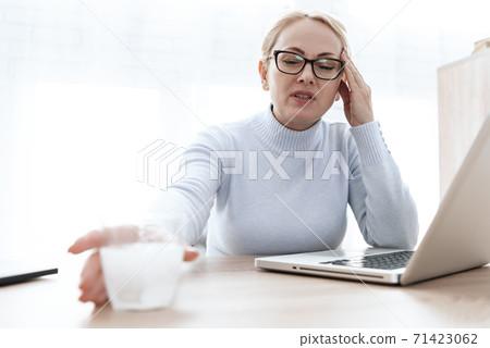 Woman sits and holds a glass with a tablet in hand Woman sits and holds a glass with a tablet in hand 71423062