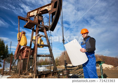 Oil man controlling work of pump jack. 71423363