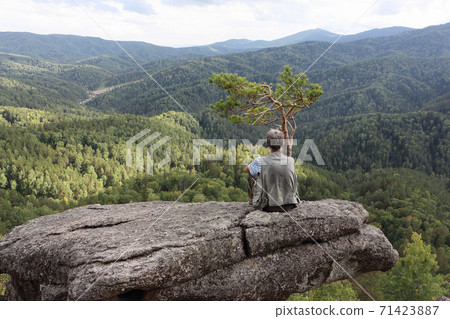 Man sitting on a rock near pine tree, Altai Man sitting on a rock near pine tree, Altai 71423887