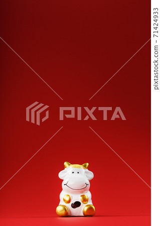 Christmas toy of a cow made of ceramic on a red background. 2021 year of the Bull, cow. New year's symbol Christmas toy of a cow made of ceramic on a red background. 2021 year of the Bull, cow. New year's symbol 71424933