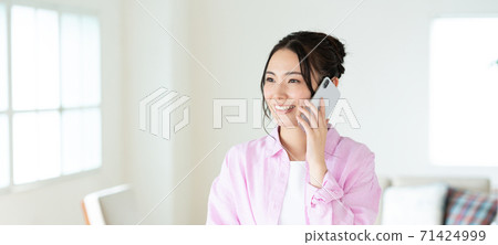 Telework A smiling young woman talking on a smartphone in the living room Banner size Telework A smiling young woman talking on a smartphone in the living room Banner size 71424999