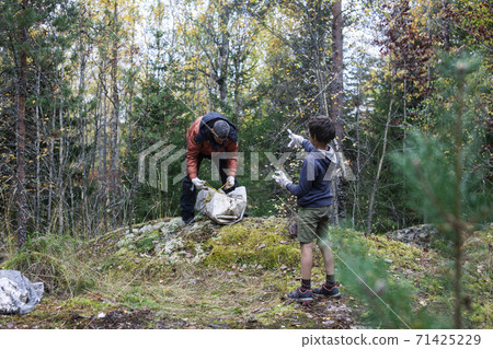 big amount of trash in forest, family father and son picking garbage away, global environment issues big amount of trash in forest, family father and son picking garbage away, global environment issues 71425229