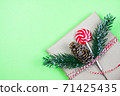 Christmas gift box wrapped in brown craft paper with corn, fir-tree and candy on green background.New Year and Christmas concept. 71425435