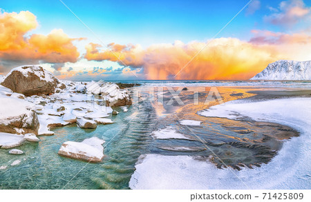 Incredible winter scenery on Skagsanden beach with illuminated clouds during sunrise. 71425809