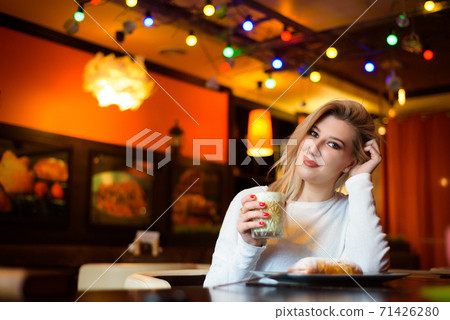 Beautiful woman drinking coffee at the cafe wintertime. Beautiful woman drinking coffee at the cafe wintertime. 71426280