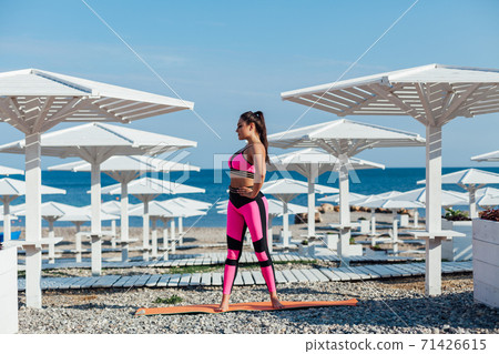 Beautiful brunette woman sports fitness gymnastics on the beach by the sea in the morning Beautiful brunette woman sports fitness gymnastics on the beach by the sea in the morning 71426615