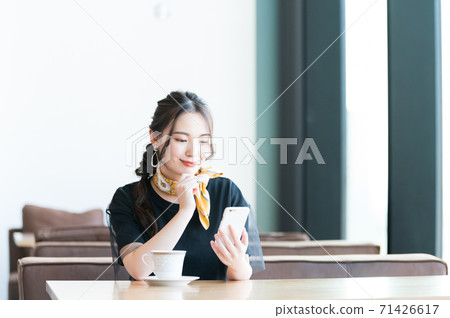 Young woman operating a smartphone in a cafe 71426617
