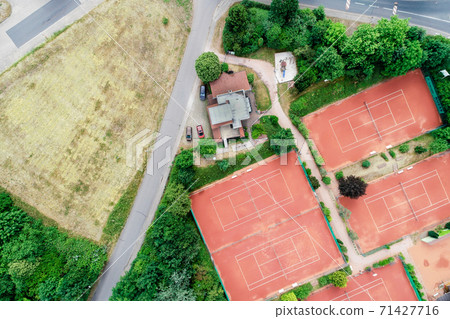 Vertical aerial view of a tennis court next to a house Vertical aerial view of a tennis court next to a house 71427716