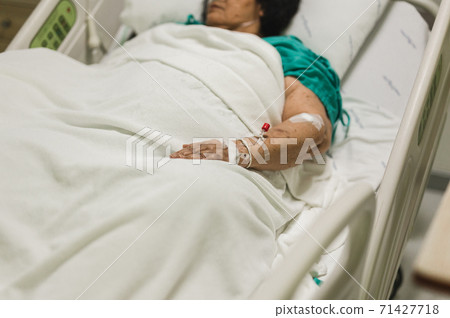 Old woman lying in bed with saline solution in hospital. Old woman lying in bed with saline solution in hospital. 71427718