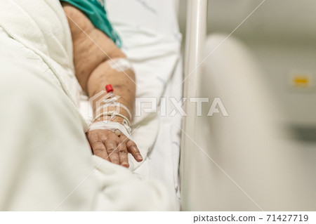 Old woman lying in bed with saline solution in hospital. Old woman lying in bed with saline solution in hospital. 71427719