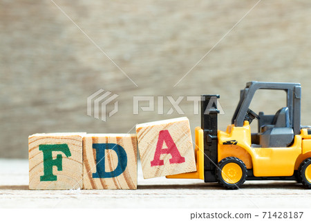 Toy forklift hold letter block A to complete word FDA (abbreviation of food and drug administration) on wood background 71428187