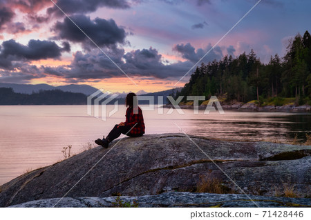 Girl Watching a Peaceful Sunrise on the Ocean Coast 71428446