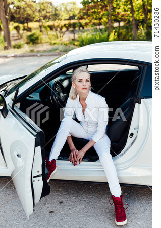Beautiful female blonde driver behind the wheel of a white car Beautiful female blonde driver behind the wheel of a white car 71430286