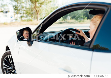 Beautiful female blonde driver behind the wheel of a white car Beautiful female blonde driver behind the wheel of a white car 71430288