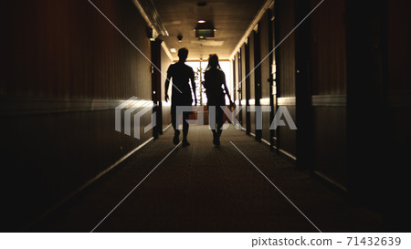 Back view of Caucasian young couple walking hotel hallway Back view of Caucasian young couple walking hotel hallway 71432639