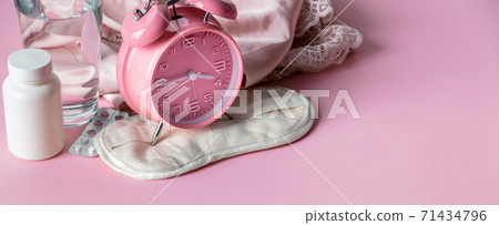 Alarm clock, eye mask, pills and glass of water on pink background Alarm clock, eye mask, pills and glass of water on pink background 71434796
