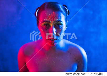 Portrait of beautiful woman painted in fluorescent powder and paint. Portrait of beautiful woman painted in fluorescent powder and paint. 71435009