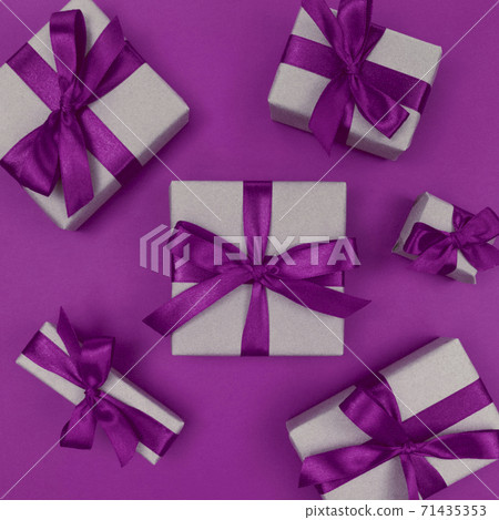 Gift boxes wrapped in craft paper with purple ribbons and bows. Festive monochrome flat lay. Gift boxes wrapped in craft paper with purple ribbons and bows. Festive monochrome flat lay. 71435353