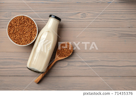 Buckwheat milk concept with bottle of milk and buckwheat grain in bowl 71435376
