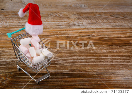 small shopping cart filled with marshmallows and Santa hat.  71435377