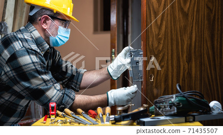 Carpenter at work protects the face with the surgical mask. Covid-19 prevention. Carpenter at work protects the face with the surgical mask. Covid-19 prevention. 71435507