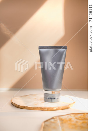 Grey cosmetic tube on neutral pastel nude background Grey cosmetic tube on neutral pastel nude background 71436111