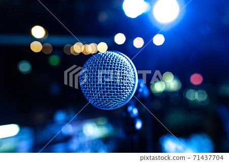 the vocalist's microphone stands on stage in the light of multicolored spotlights 71437704