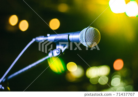 singer's vocal microphone stands on stage during a concert with multi-colored lights on the background singer's vocal microphone stands on stage during a concert with multi-colored lights on the background 71437707