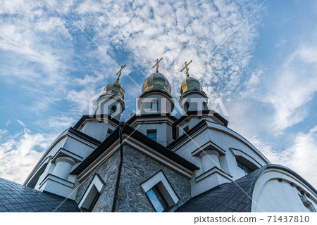 three towers of the Orthodox Christian Church of St. Eugene with cupola domes and crosses in the village. Buky, Ukraine 71437810