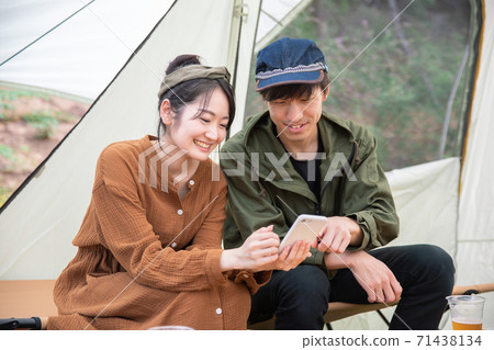 Asian men and women using smartphones at the campsite Asian men and women using smartphones at the campsite 71438134