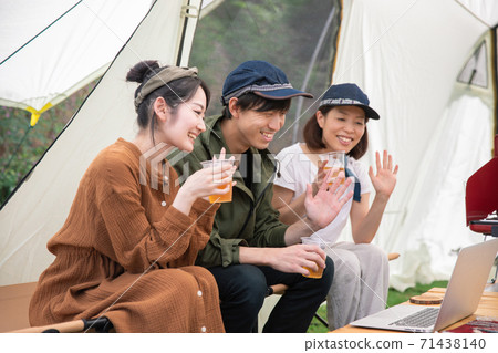 Asian men and women working remotely using a laptop at a campsite 71438140