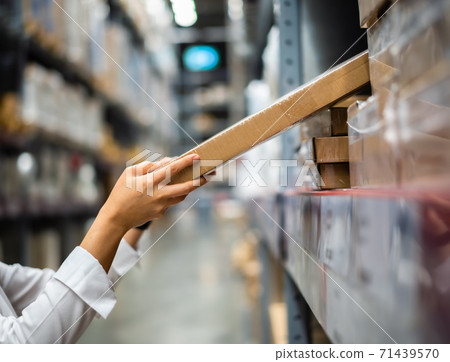 hand is picking up a box in warehouse store 71439570