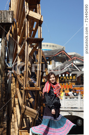 chinese girl model at Lijiang dancing in front of big waterwheel woman in lijiang old town, the world heritage site of UNESCO chinese girl model at Lijiang dancing in front of big waterwheel woman in lijiang old town, the world heritage site of UNESCO 71440490
