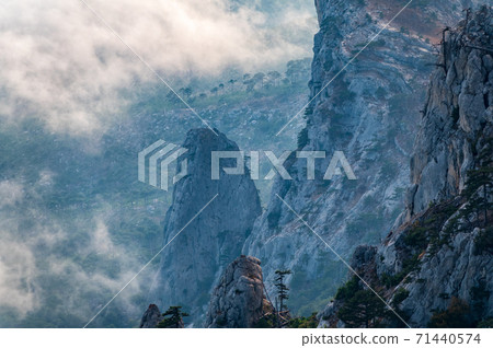 A majestic view of the rocky mountains and the valley in fog and clouds. Creamy fog covered the mountain valley in sunset light. Picturesque and gorgeous scene. Misty sunset over Crimea Mountains 71440574