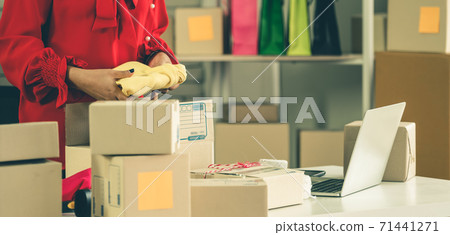 Online seller works at home office and packs shipping delivery box to customer. Online seller works at home office and packs shipping delivery box to customer. 71441271