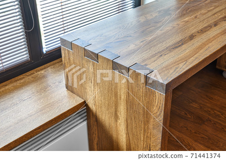 Modern furniture. Box joint solid wooden desk against the background of the window 71441374