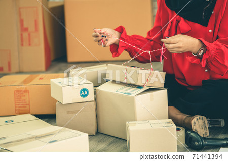 Online seller works at home office and packs shipping delivery box to customer. Online seller works at home office and packs shipping delivery box to customer. 71441394