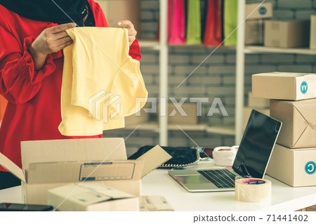 Online seller works at home office and packs shipping delivery box to customer. Online seller works at home office and packs shipping delivery box to customer. 71441402