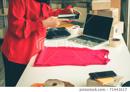 Online seller works at home office and packs shipping delivery box to customer. Online seller works at home office and packs shipping delivery box to customer. 71441617