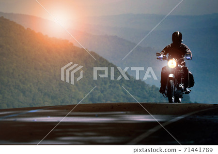 man riding motorcycle on mountain highway 71441789