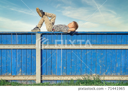 Boy resting and dreaming on hockey rink fence against cloudy sky Boy resting and dreaming on hockey rink fence against cloudy sky 71441965